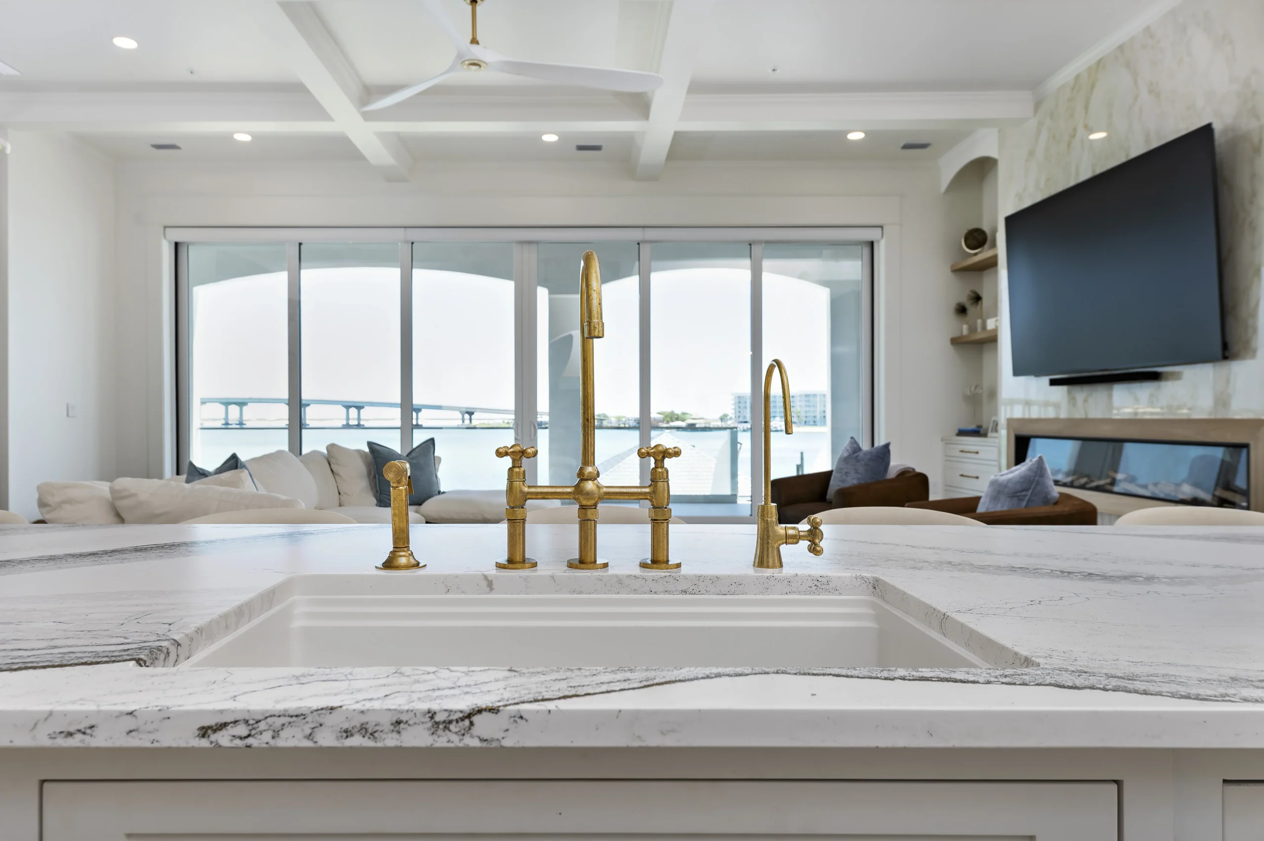 Quartzite kitchen island with an undermount sink and brass bridge faucet
