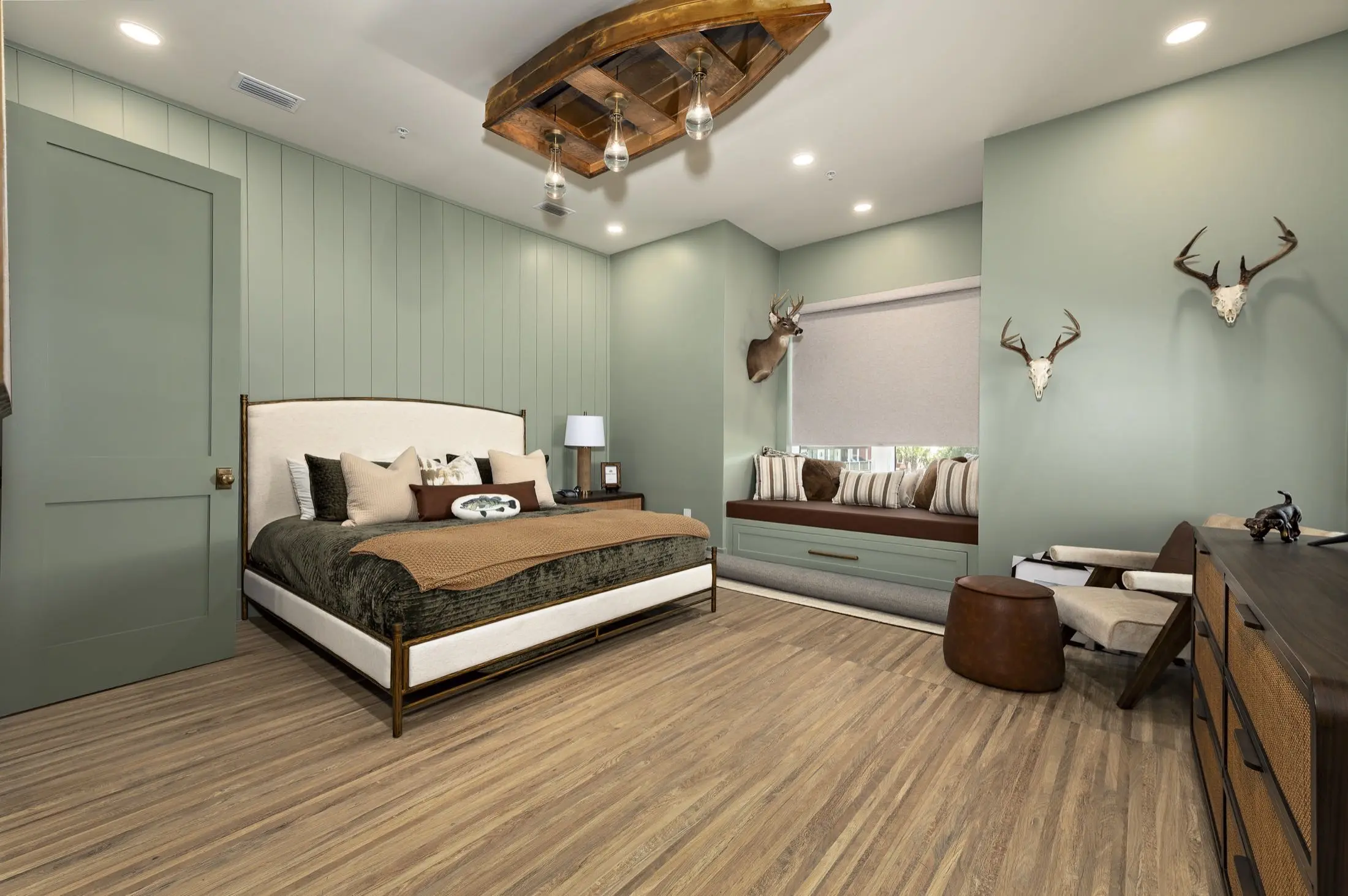 Remodeled bedroom with sage green shiplap walls and wide plank flooring