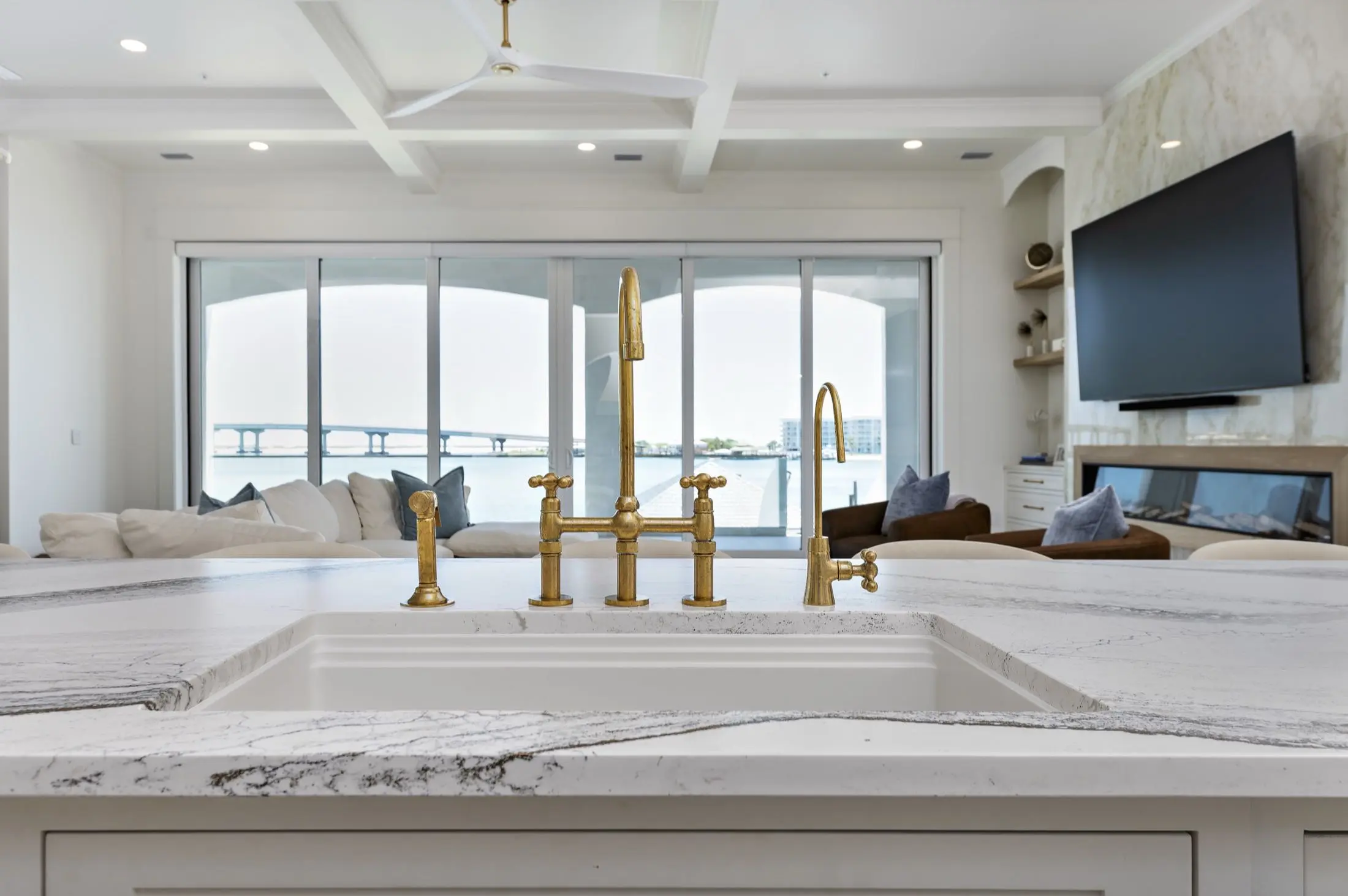 Brass bridge faucet on a veined stone kitchen island with water views in Orange Beach AL