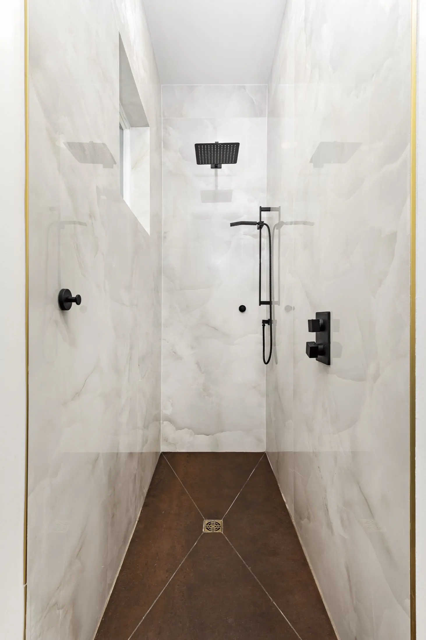 Walk-in shower with white onyx-look slab walls and matte black fixtures