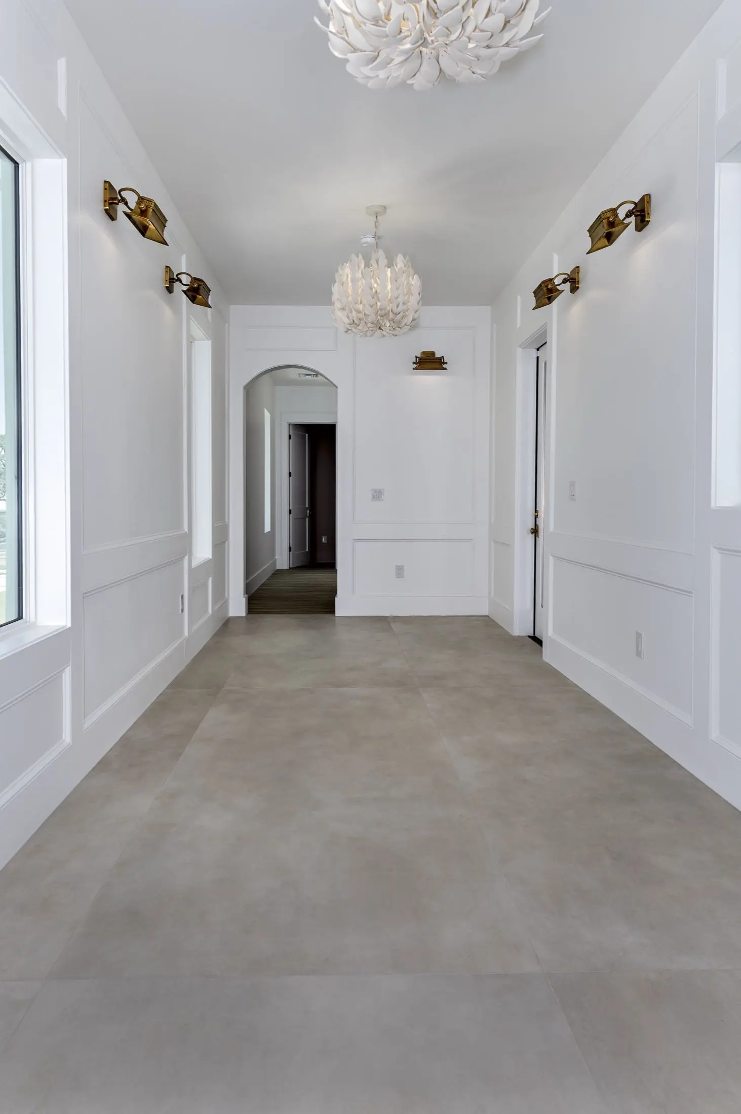 Entry hall with large-format stone tile flooring and brass sconces in an Orange Beach AL home