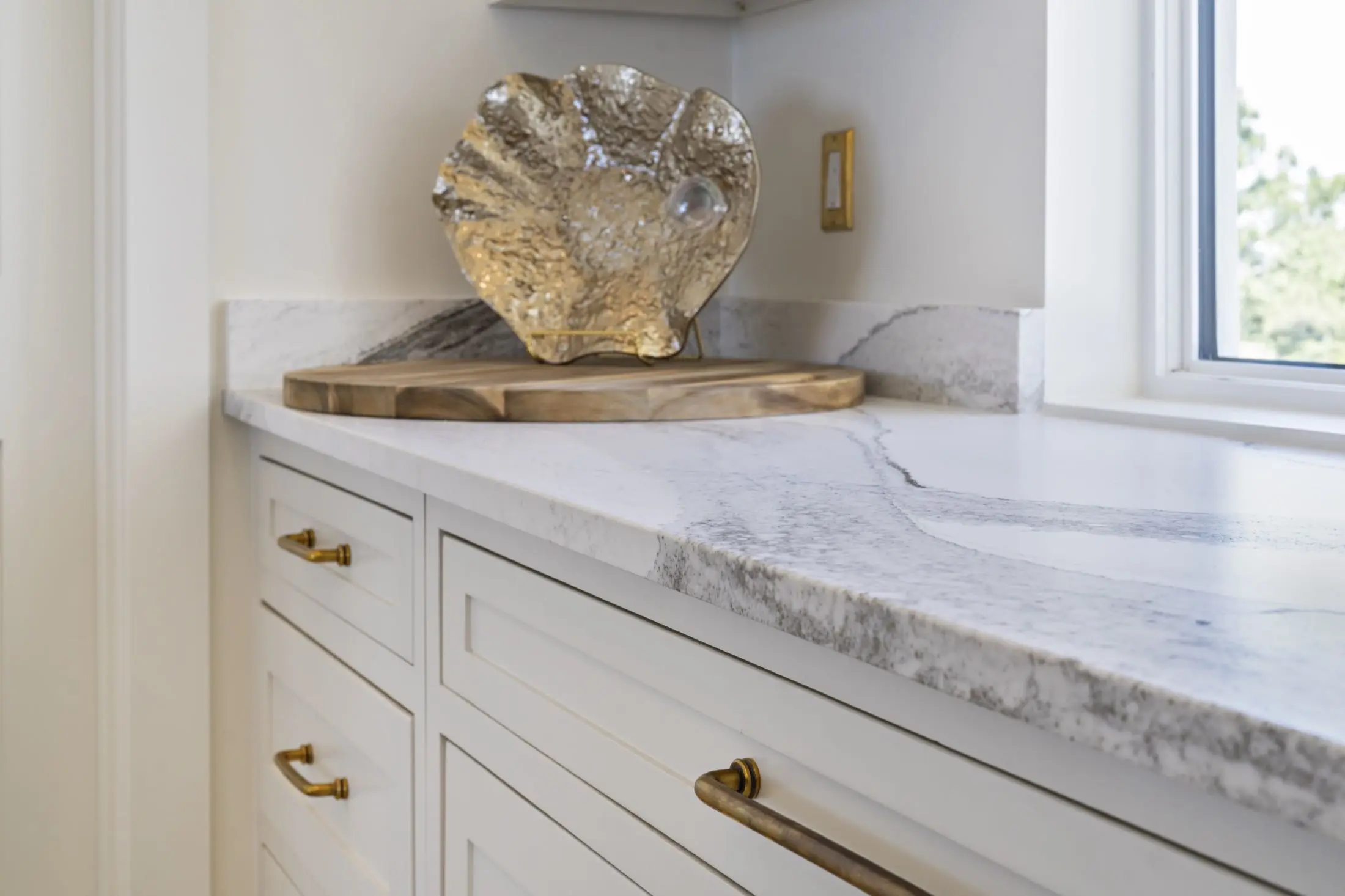 Marble countertop with soft grey veining and brass cabinet hardware