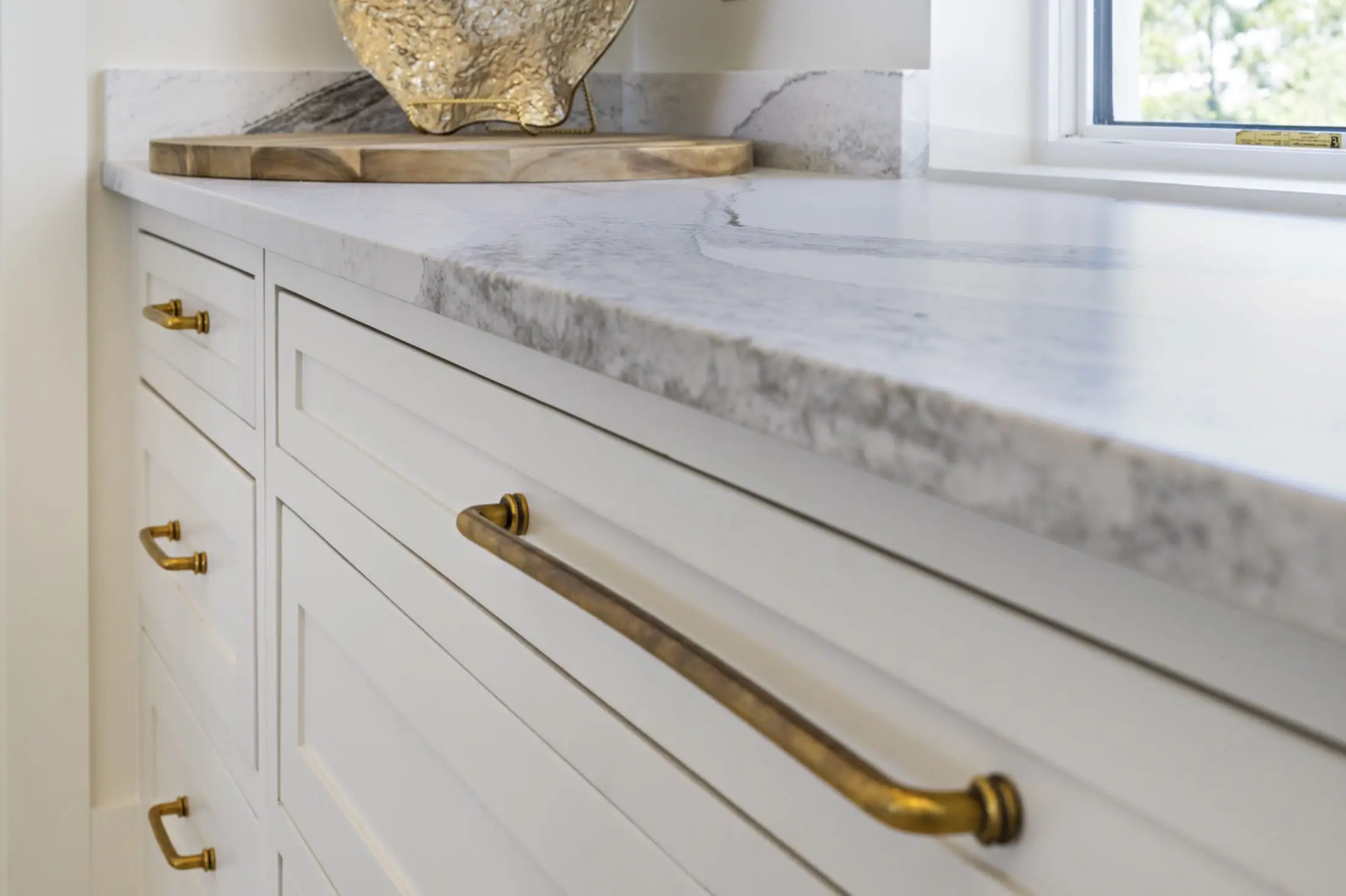 Close-up of a honed marble countertop with brass cabinet pulls