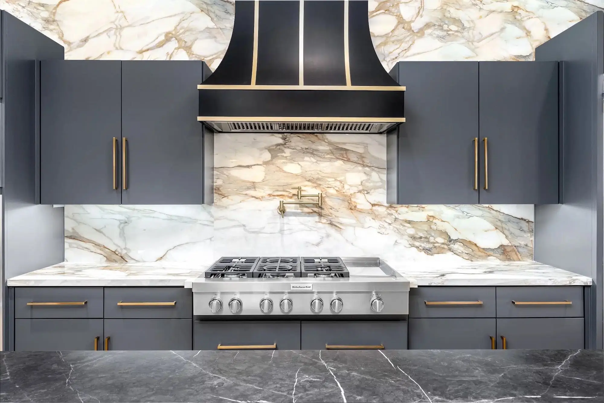 Porcelain kitchen countertops and matching slab backsplash in a navy kitchen